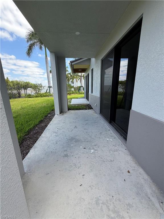 The property features a concrete patio area with a view of a lush green lawn and mature palm trees