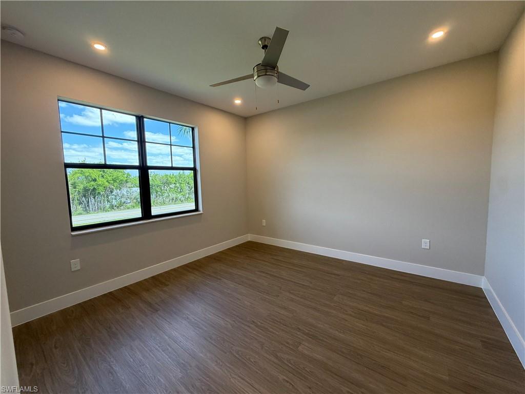This room features a large window with views of lush greenery and the sky, wood-look flooring, and recessed lighting