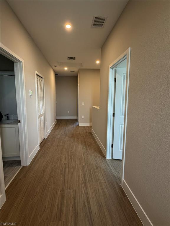 Hallway featuring wood-look flooring, recessed lighting, and a neutral color palette