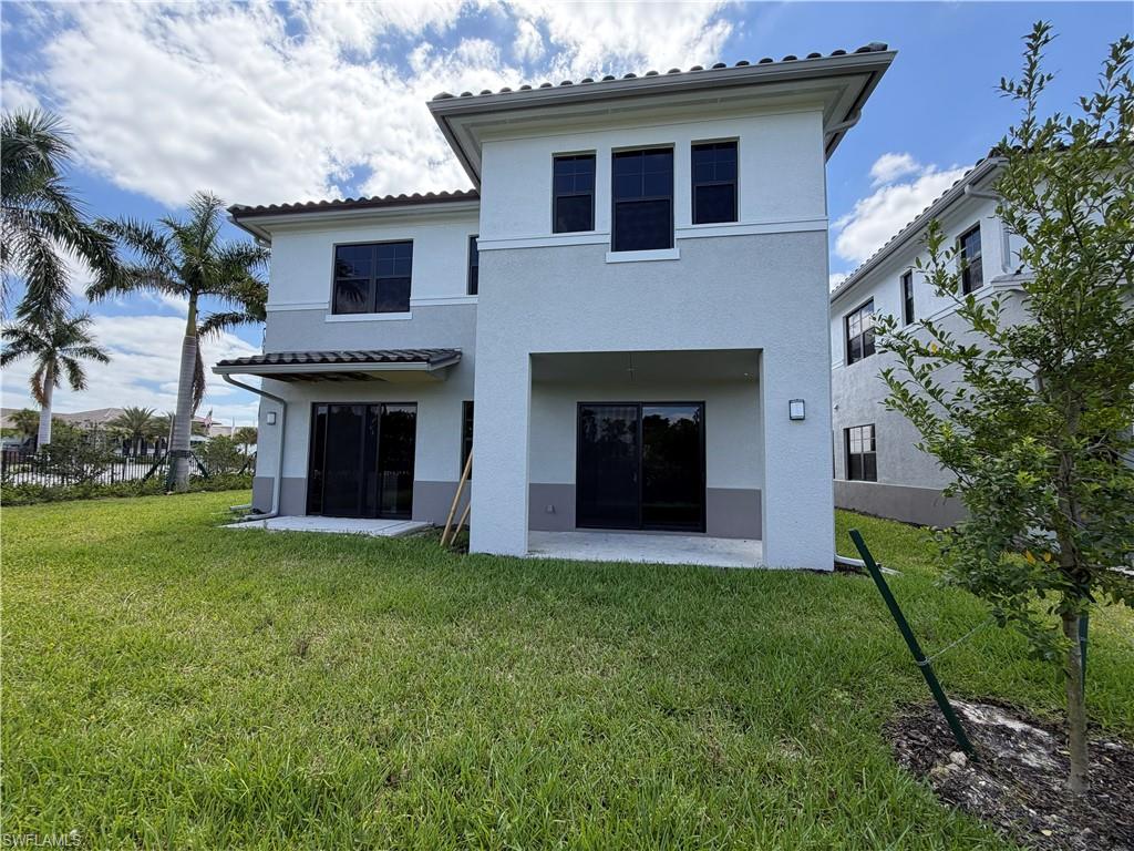 The property features a stucco exterior with a tiled roof and an extensive yard with a lawn