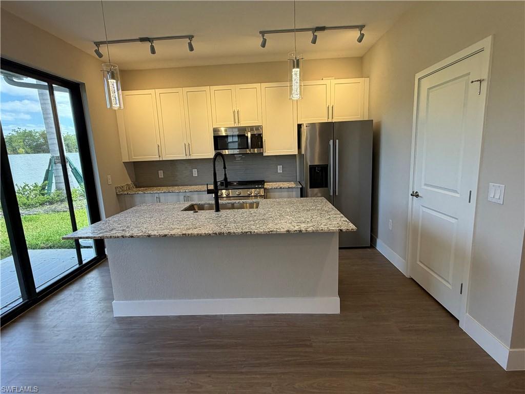 The kitchen features granite countertops, a large island with an undermount sink, stainless steel appliances, and ample cabinetry