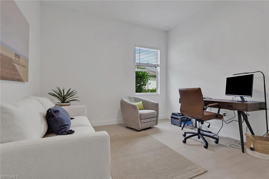 Bright interior space with light wood-finish flooring, white walls, and a window featuring blinds