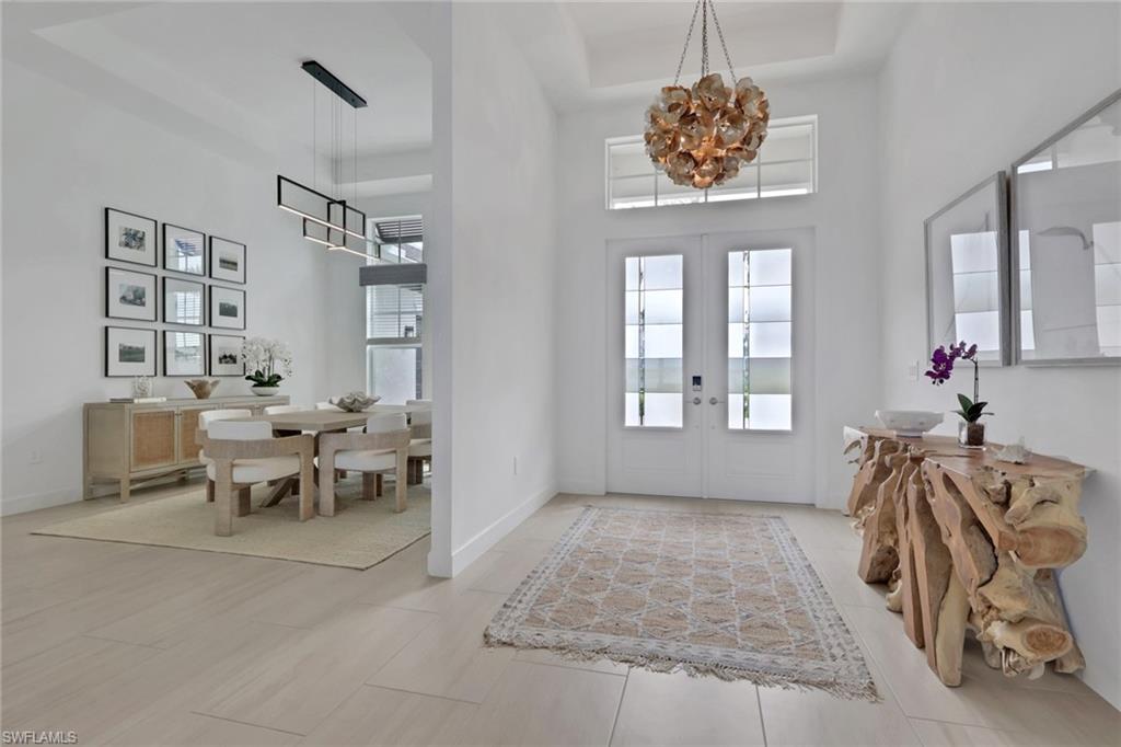 Foyer with double entry doors and transom window, featuring a decorative chandelier and light wood-finish flooring