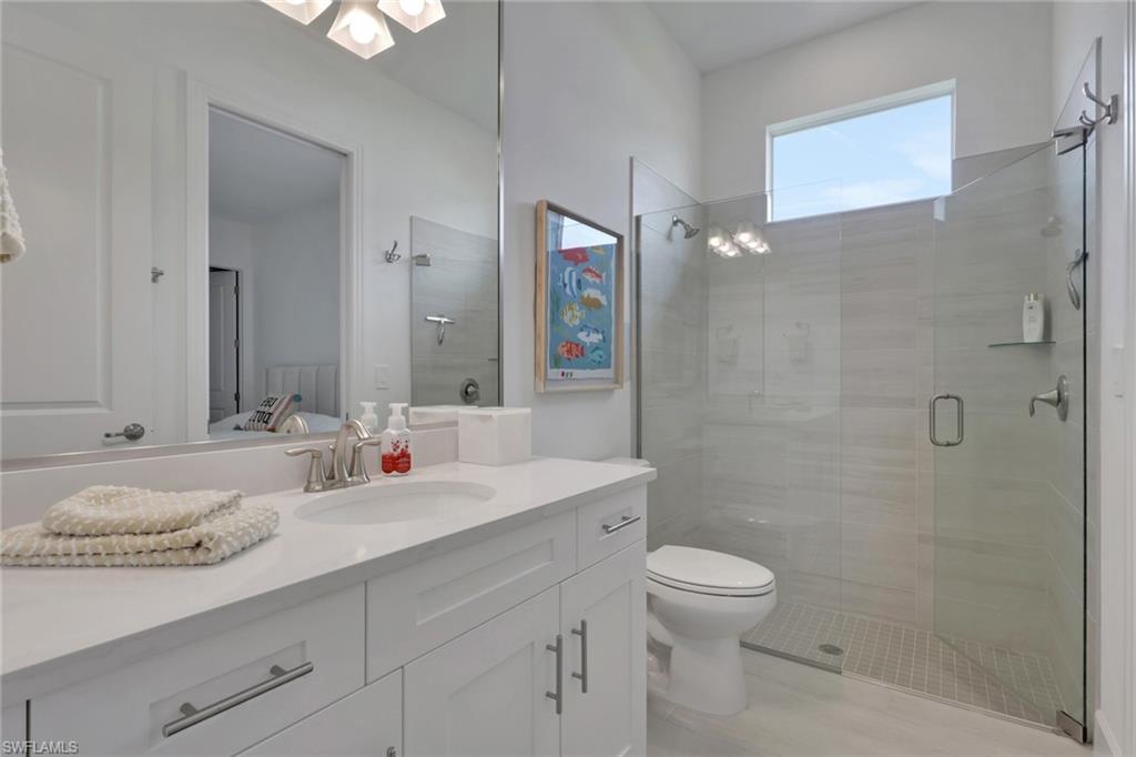 Modern bathroom featuring a single vanity with shaker-style cabinetry, a solid surface countertop, and a rectangular sink