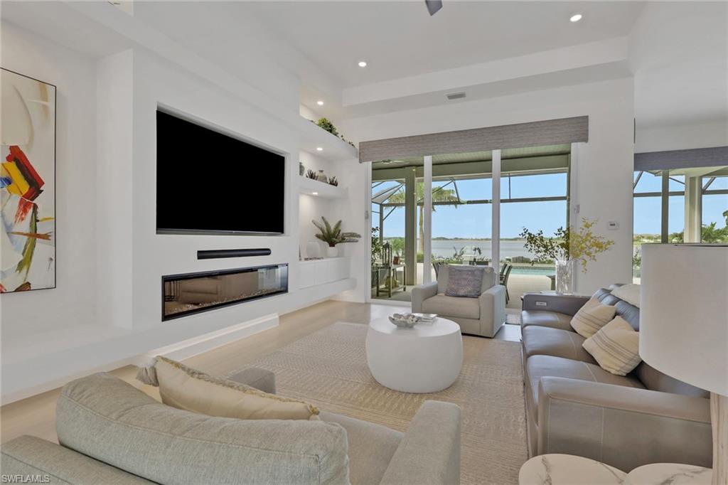 Living room featuring an integrated media wall with a wide-screen display, linear fireplace, and built-in shelving