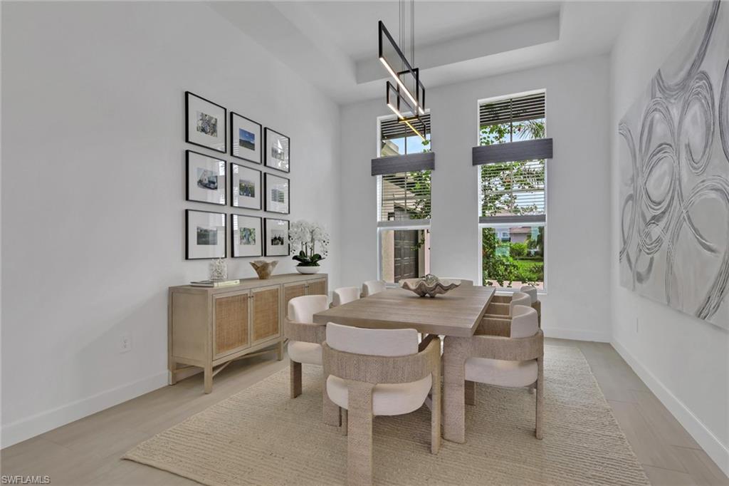 Tall windows with integrated blinds, a linear ceiling light fixture, and light-toned wood-finish flooring