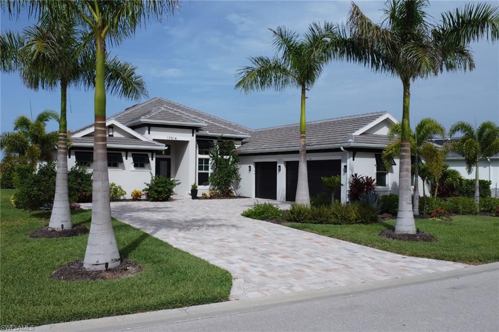 Contemporary single-story residence featuring a tile roof, a paver driveway, and a two-car garage with dark doors