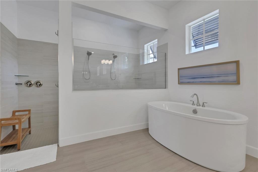 Freestanding soaking tub with a deck-mounted faucet and an expansive walk-in shower featuring a glass enclosure