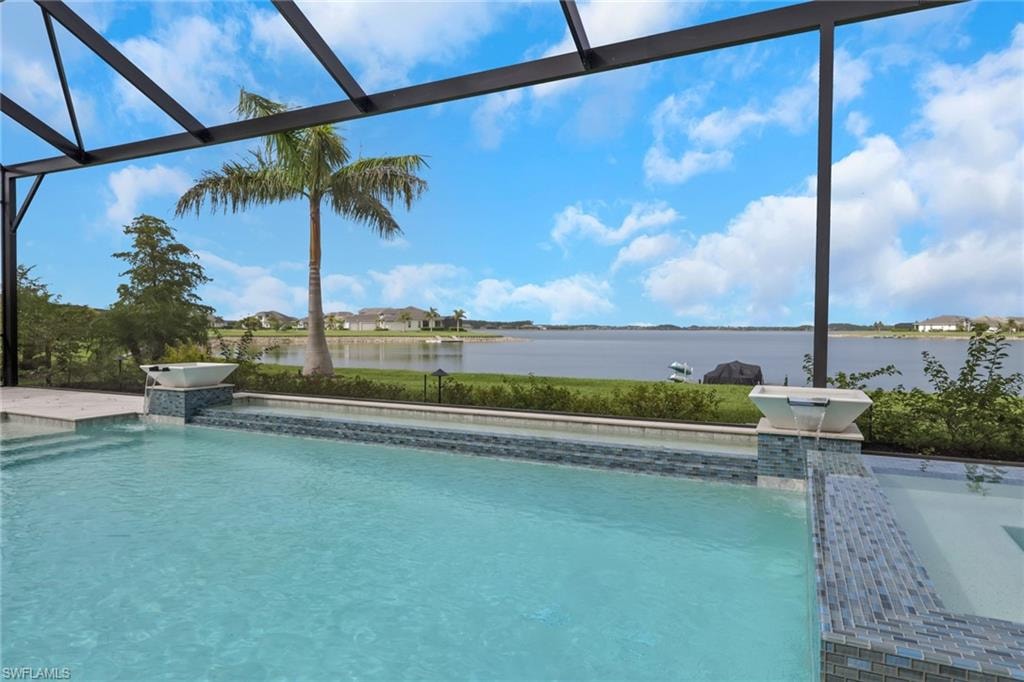 Screened lanai featuring a swimming pool with integrated spa and decorative water features