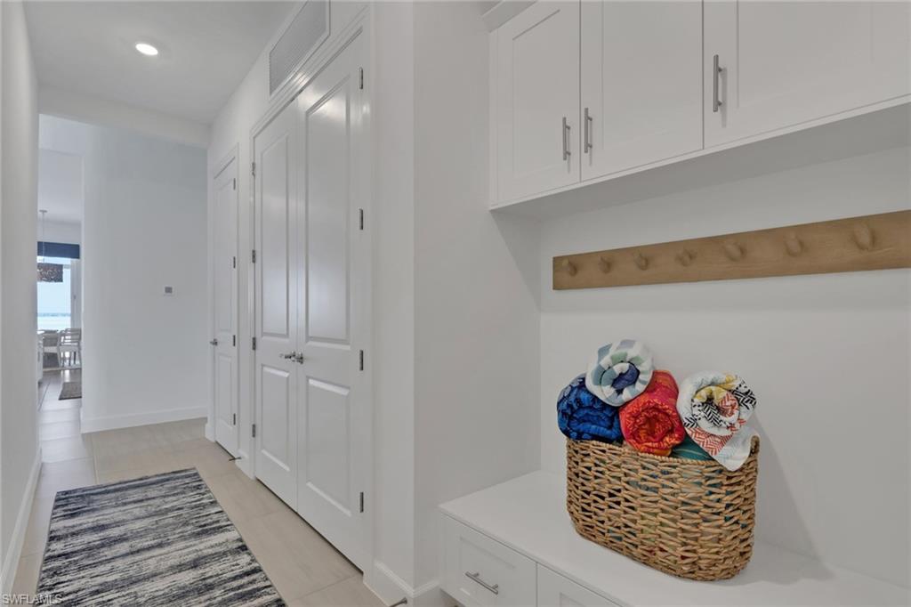 Entryway featuring built-in white cabinetry, a natural wood-finish coat rack, and light-toned tile flooring