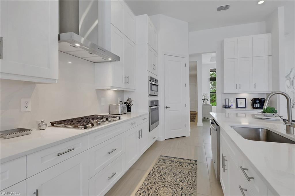Modern kitchen featuring extensive white cabinetry, light-toned countertops, and tile flooring