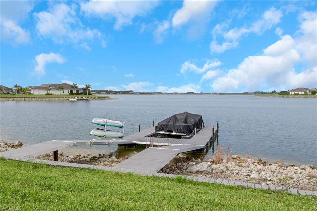 Lakefront property featuring a private dock with boat lift and kayak storage, extensive water frontage, and lush green lawn