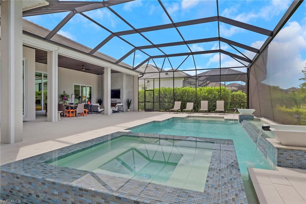 Screened outdoor living area featuring a pool, integrated spa with mosaic tile surround, and a covered lanai