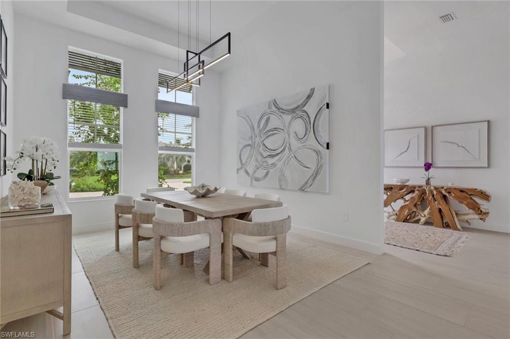 Dining area featuring tall windows, contemporary linear pendant lighting, high ceilings, and light wood-finish flooring