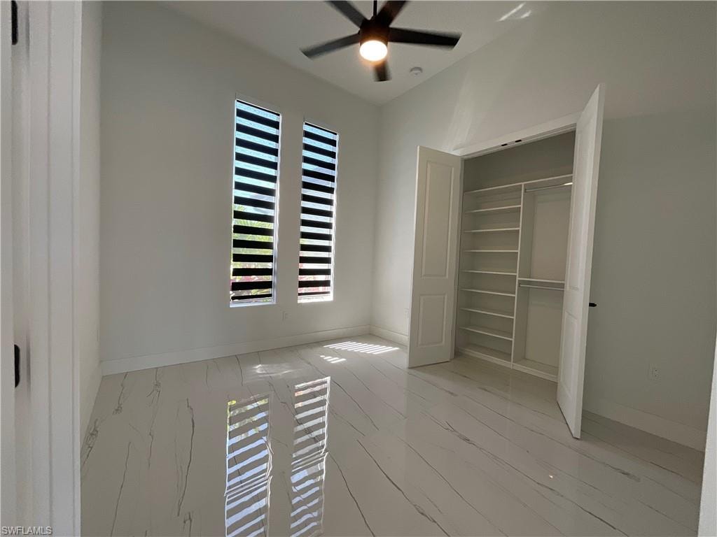 Room featuring two vertical windows with blinds, a ceiling fan with light, and light-toned flooring