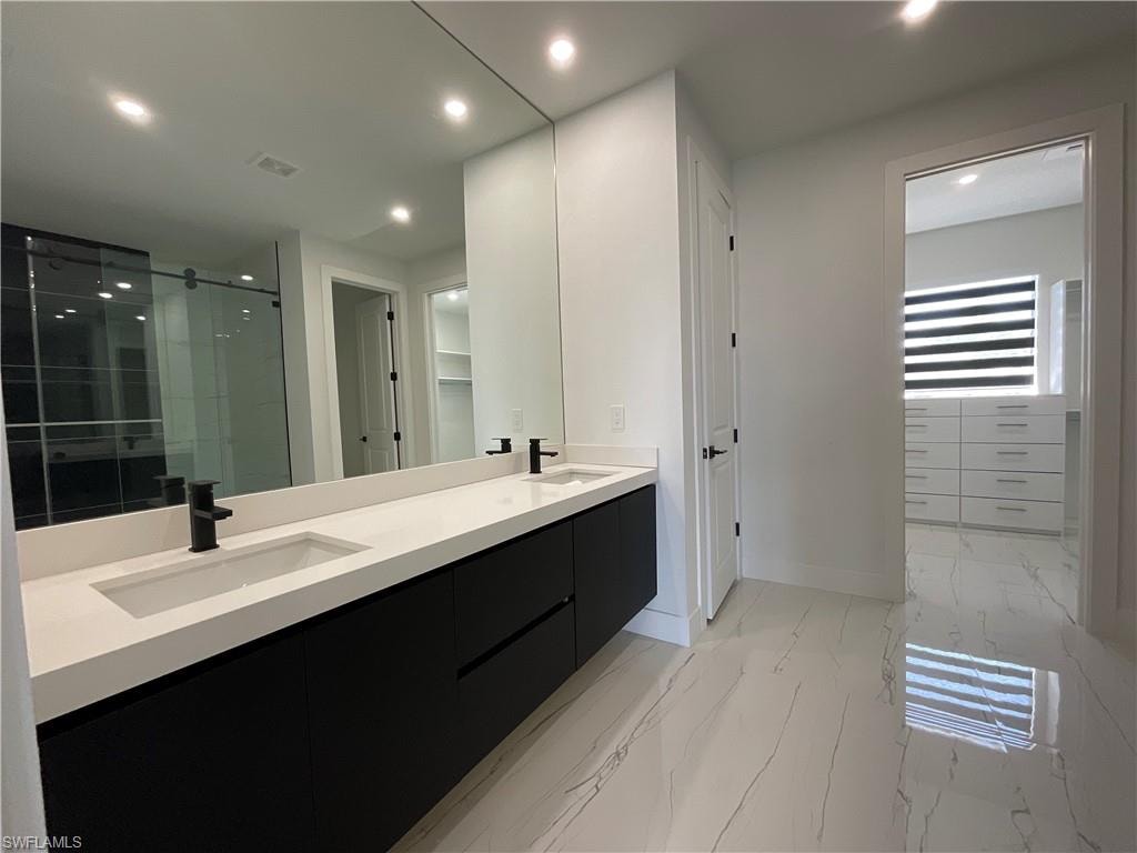 Bathroom featuring a large double vanity with black cabinetry and white countertops, under-mount sinks, and matte black faucets