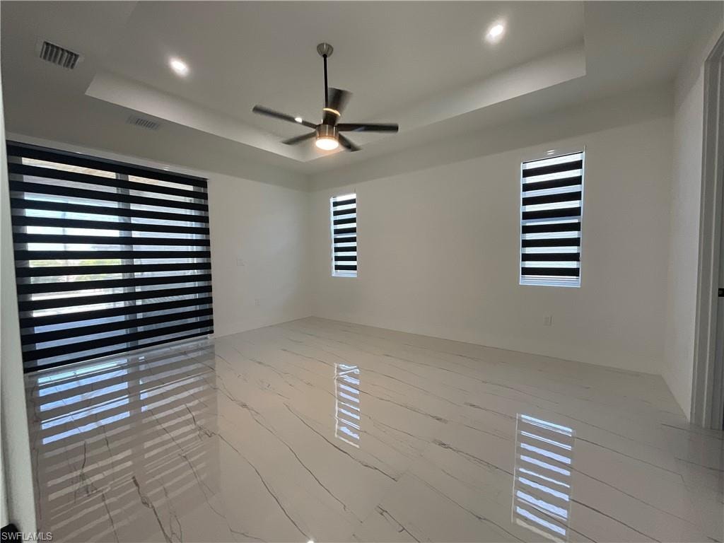 Spacious room featuring elegant white floors with dark veining, a contemporary ceiling fan, and recessed lighting