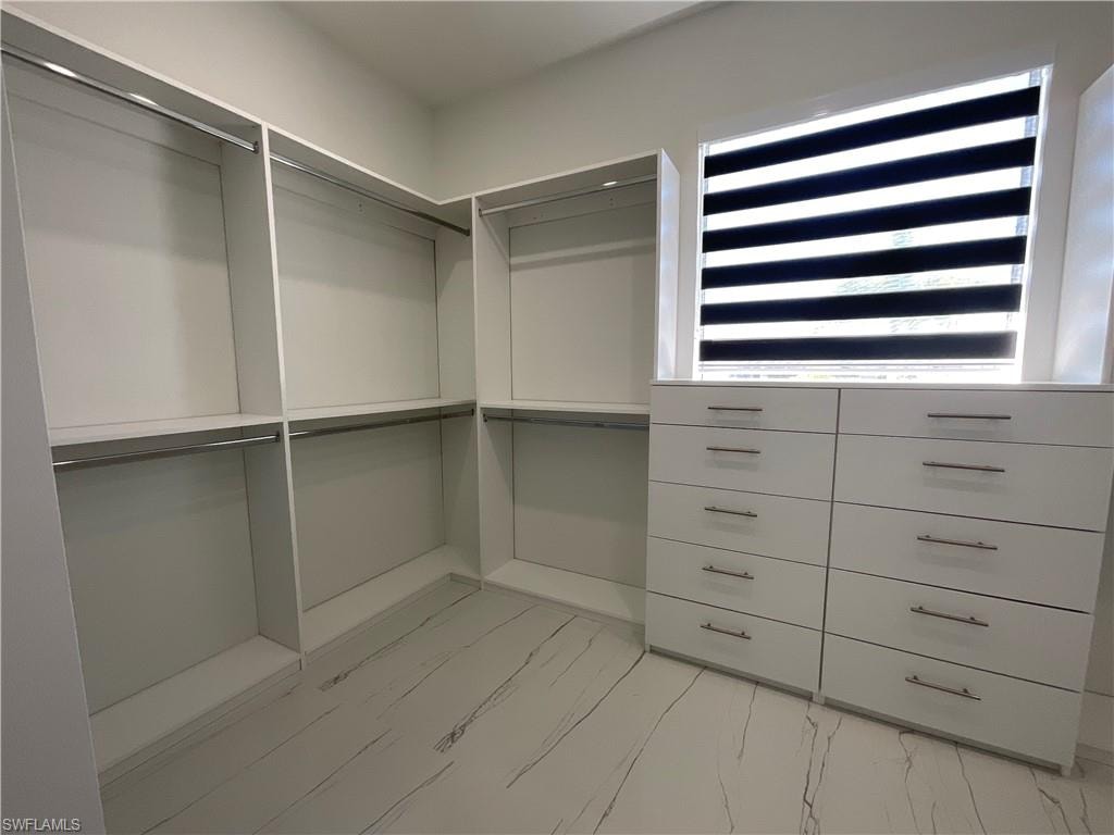 Well-appointed closet featuring built-in shelving, hanging rods, and a window for natural light