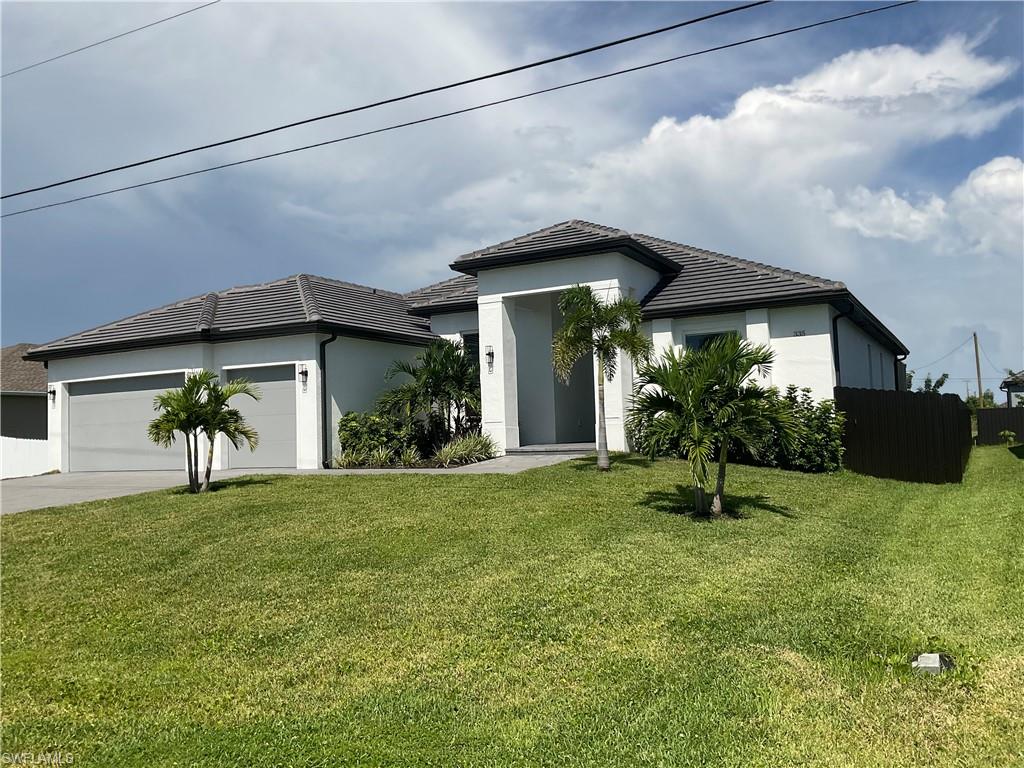 Contemporary stucco exterior with a tiled hip roof, integrated two-car garage, and established landscaping