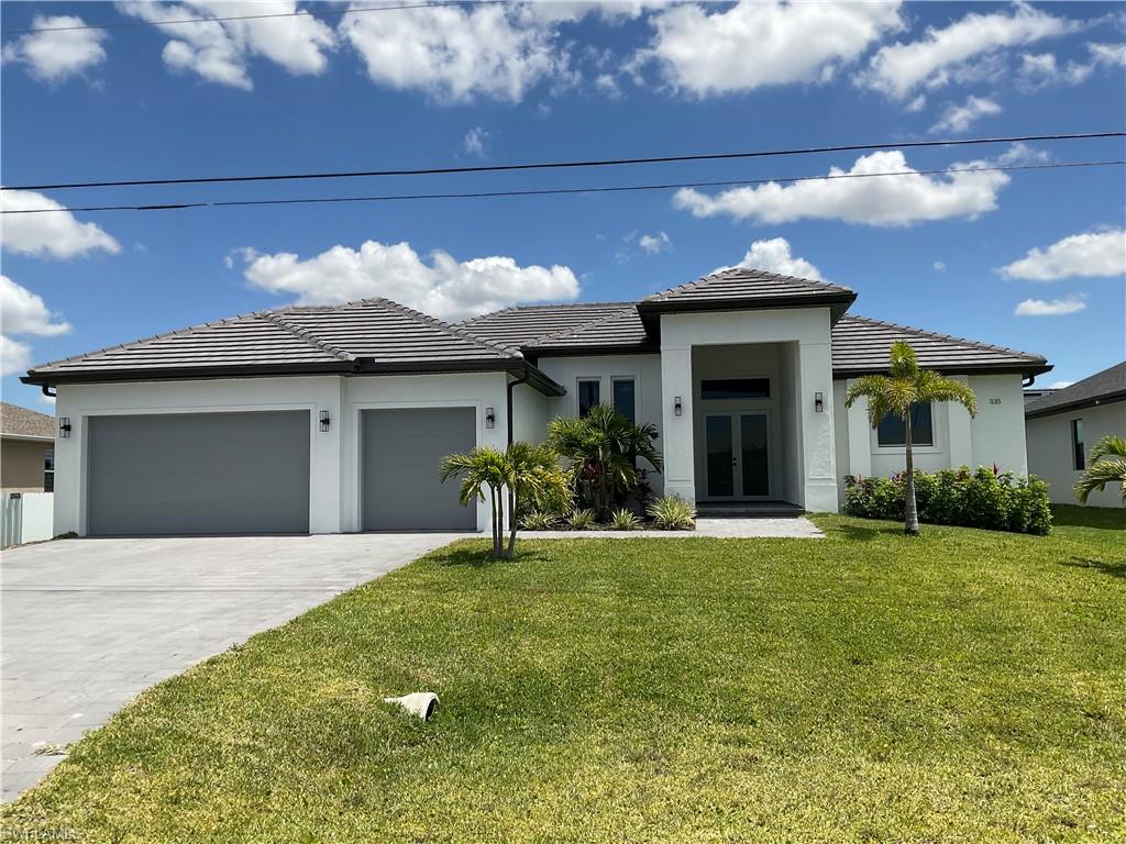 The property features a well-maintained lawn, a concrete driveway leading to a two-car garage, and an inviting entryway