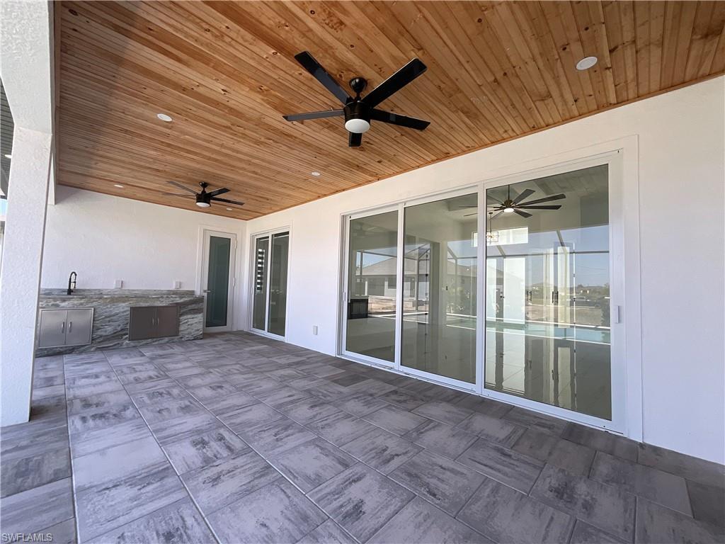 Expansive outdoor living area featuring a wooden ceiling with recessed lighting and ceiling fans, tiled flooring, and sliding glass doors