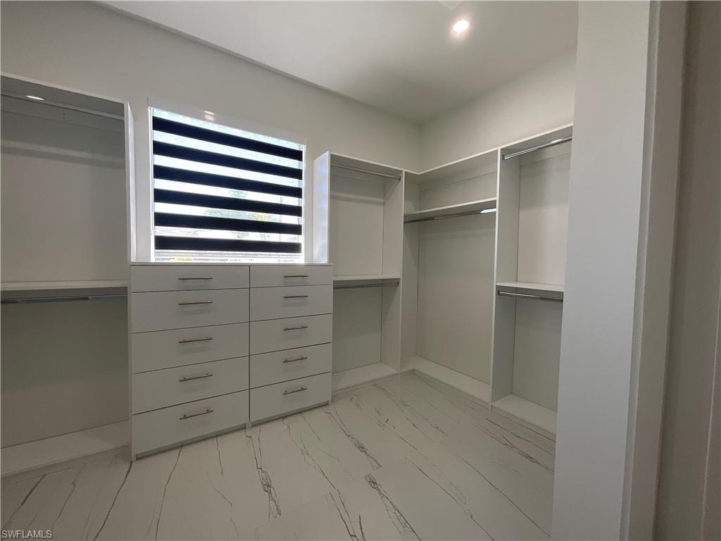 Well-appointed closet space featuring built-in shelving, hanging rods, and a window with blinds