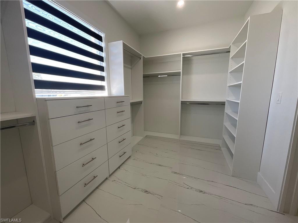 This property features an organized closet space with built-in shelving, hanging rods, and a dresser unit with drawers
