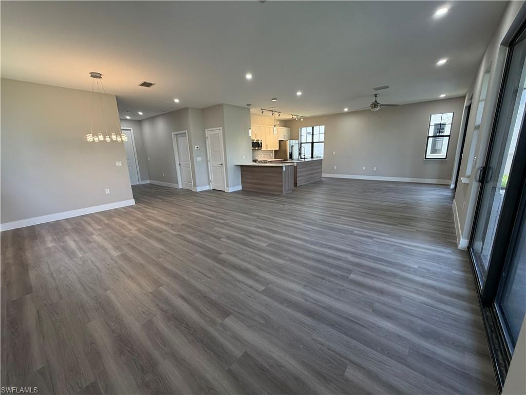 Expansive open-concept living area featuring light-toned flooring, recessed lighting, and a modern chandelier