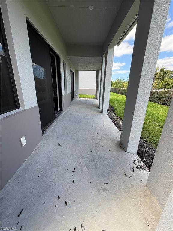 The property features a covered patio with a concrete floor, offering views of a grassy area