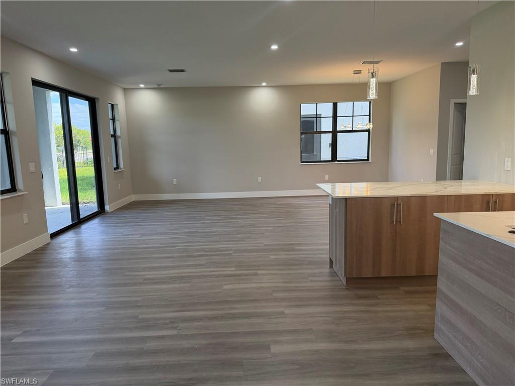 This open-concept living area features light-colored plank flooring, recessed lighting, and sliding glass doors that open to an outdoor patio
