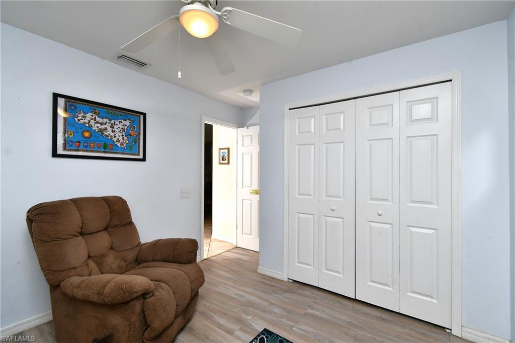 This room features light blue walls, light-colored wood-style flooring, and a ceiling fan
