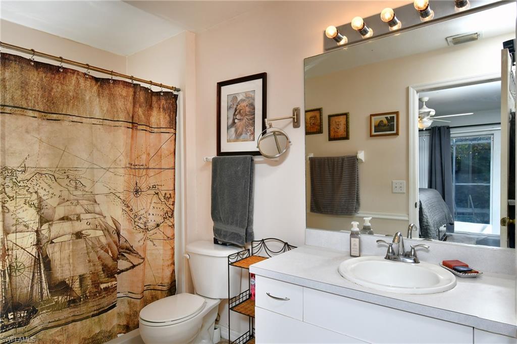 Bathroom featuring a white vanity with an integrated sink, a large mirror, and a toilet