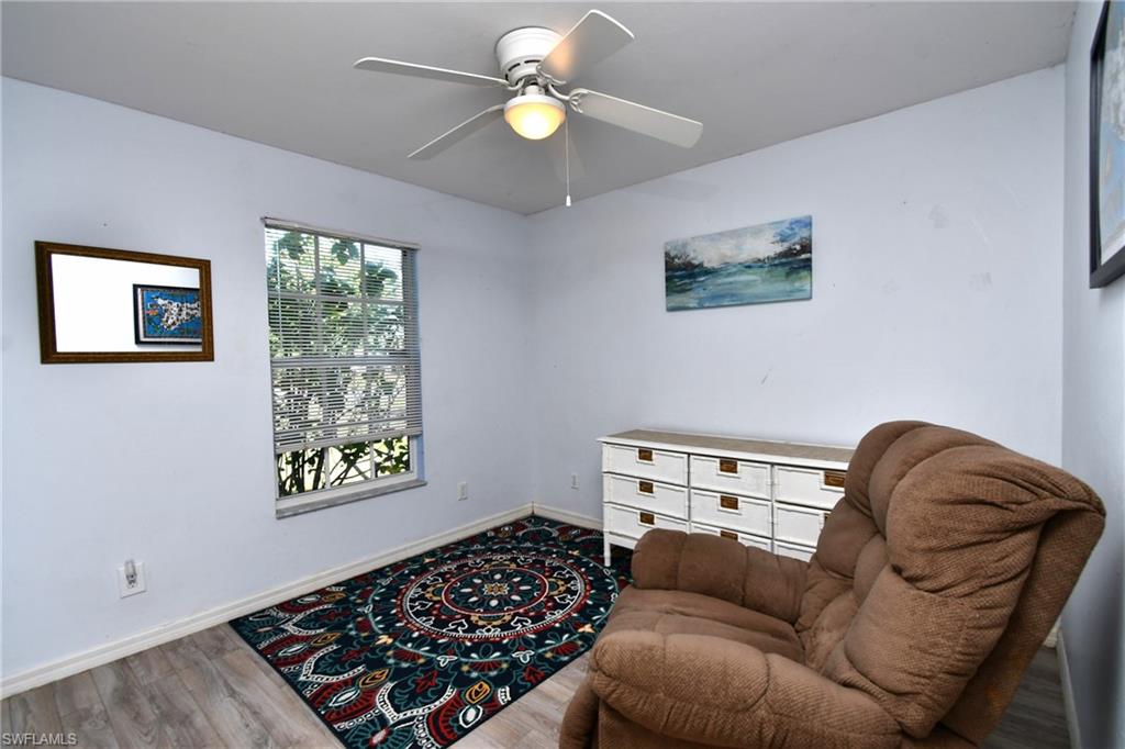 The room features a window with blinds, a ceiling fan with an integrated light fixture, and wood-look flooring