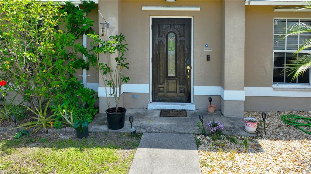 The property features a front entrance with a decorative dark wood door and an adjacent window with white muntins, set against a neutral-toned facade with white trim