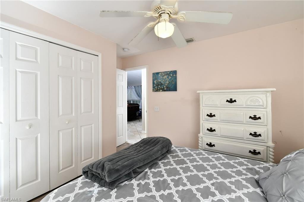 This room features light pink walls, a ceiling fan with a light fixture, and white bi-fold closet doors