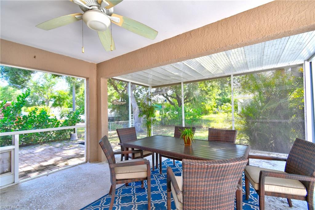 Expansive screened patio featuring a ceiling fan, outdoor dining area, and views of the surrounding greenery