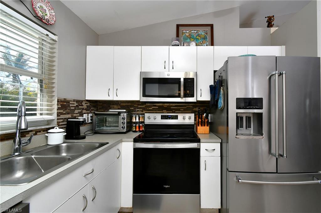 The kitchen features a stainless steel refrigerator, microwave, and range, complemented by white cabinetry and a tiled backsplash