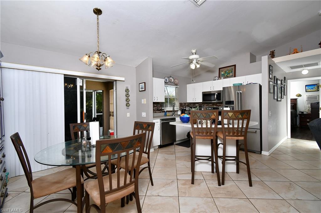 The kitchen features stainless steel appliances, white cabinetry, a kitchen island with seating, and a ceiling fan