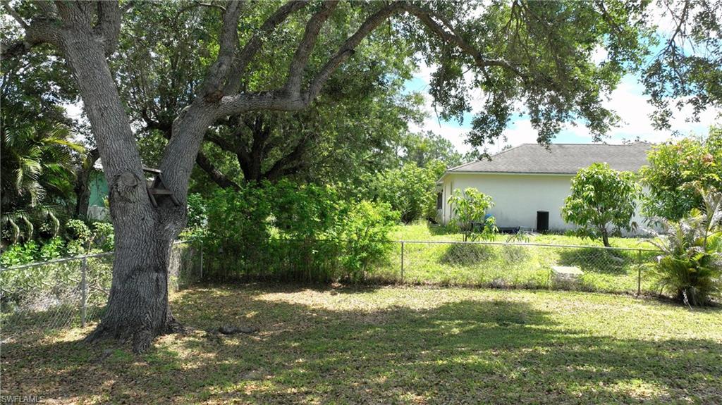 The property features an extensive outdoor area with mature trees, a well-maintained lawn, and a chain-link fence