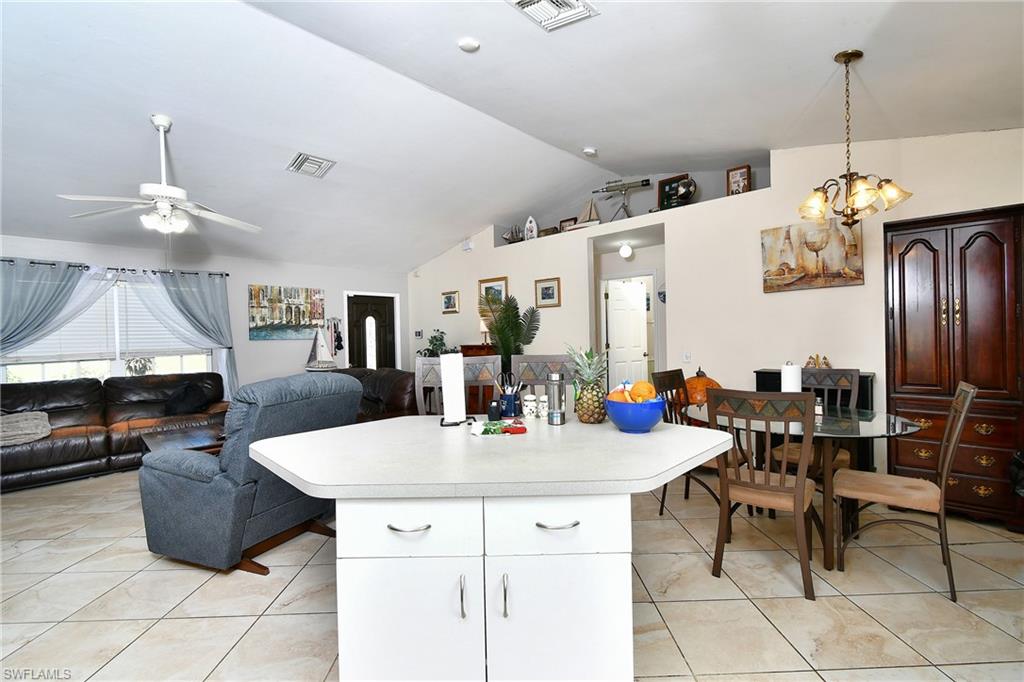 The open concept living area features vaulted ceilings, tile flooring, and a kitchen island with a light-colored countertop
