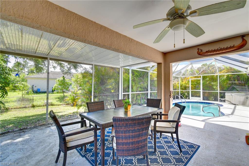 The screened-in patio features a ceiling fan, an outdoor dining table with chairs, and a pool area with a hot tub
