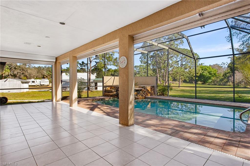 Spacious screened lanai with white tile flooring, offering direct access to an in-ground swimming pool with brick-style paver coping