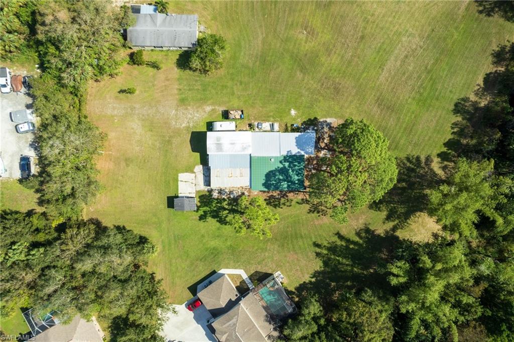 Expansive property featuring a central building with a metal roof, surrounded by extensive green space