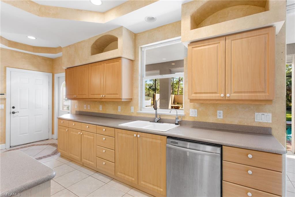 Kitchen featuring light wood cabinetry, a double basin sink, and integrated stainless steel dishwasher