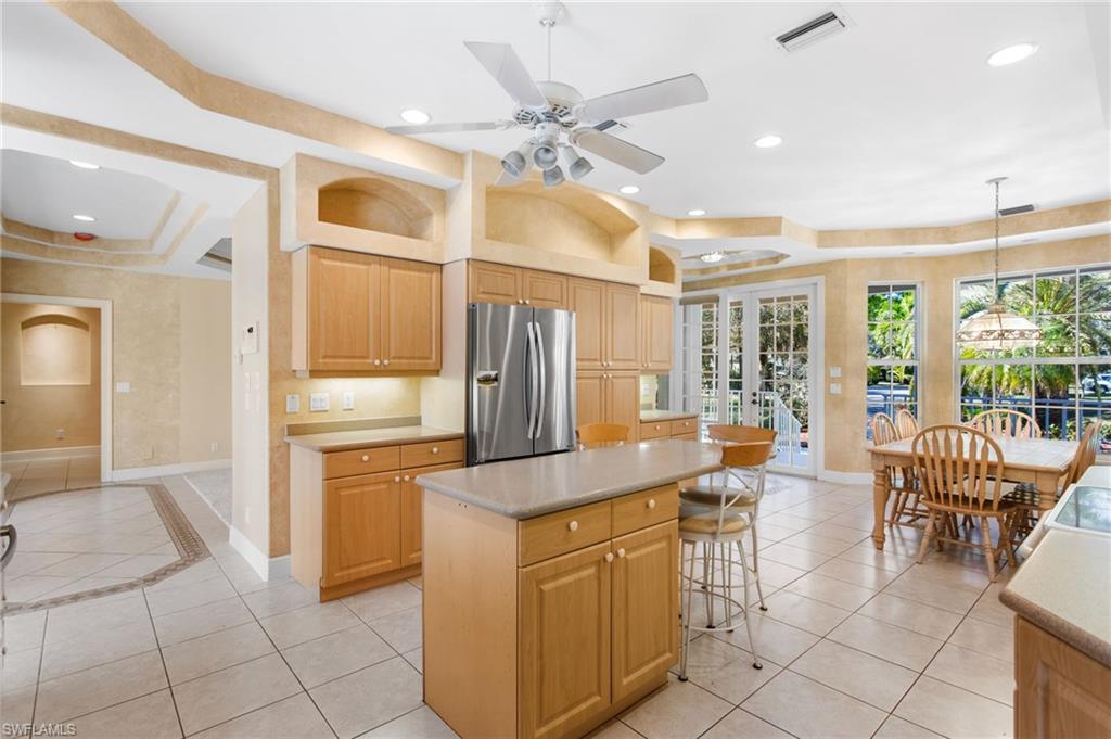Kitchen featuring light wood cabinetry, stainless steel refrigerator, and a central island with countertop seating