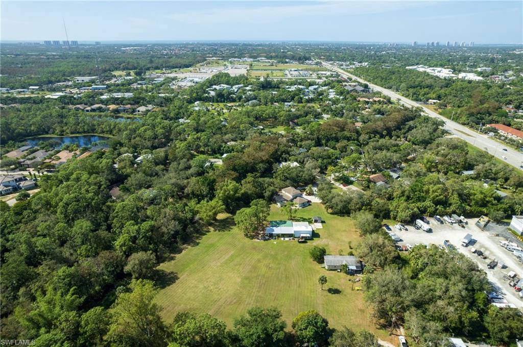 Expansive green lot featuring mature trees and a single-story residence with a light-colored roof