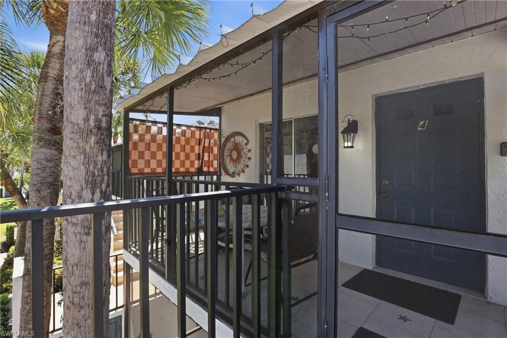 Screened-in balcony featuring a privacy screen, outdoor lighting, and tile flooring