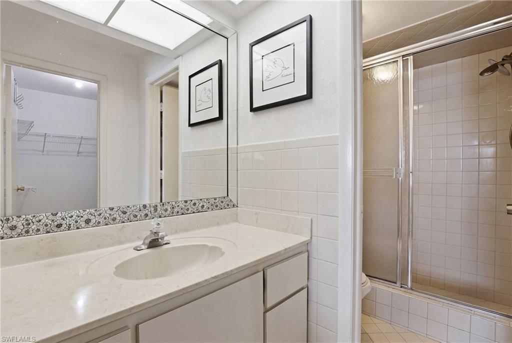 Bathroom vanity featuring a light-toned countertop with integrated sink, chrome faucet, and a large wall-mounted mirror