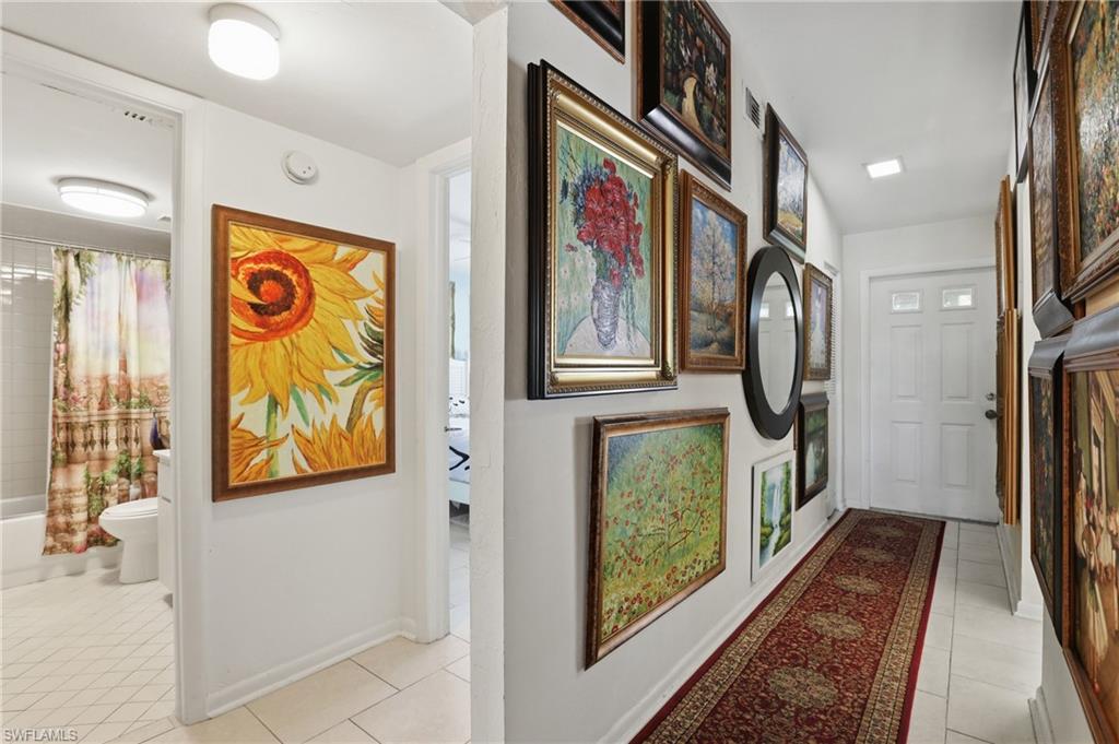 Hallway with white tile flooring and overhead lighting