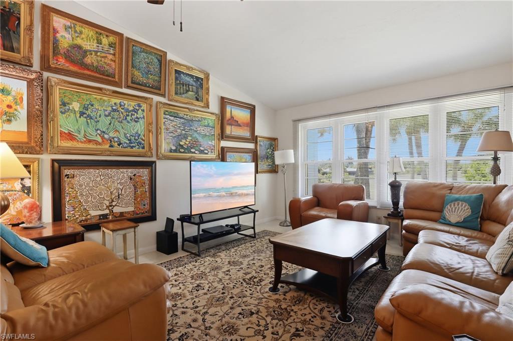 Spacious living area featuring a vaulted ceiling and large windows with horizontal blinds